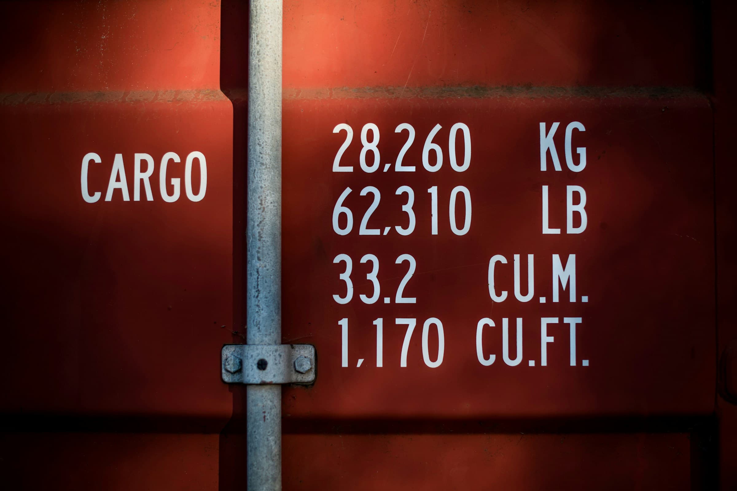 Stenciled cargo weight and volume markings on the side of a shipping container